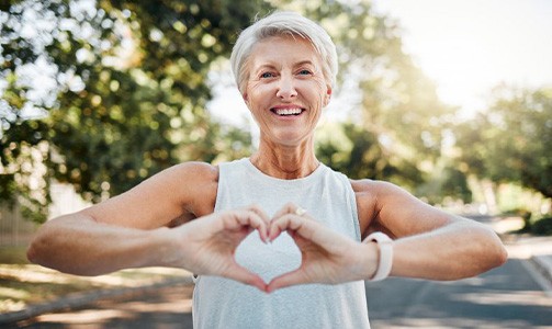 Smiling lady makes shape of heart with her hands