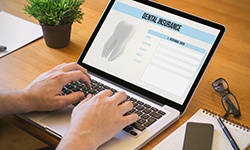 Patient filling out dental insurance form on laptop