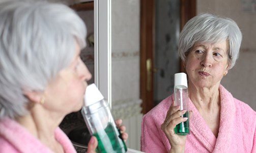 Patient in Idaho Falls smiling at dentures in mirror