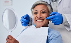 Woman smiling while holding handheld mirror
