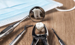 Forceps holding tooth and lying on wooden table