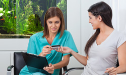 Dental patient handing dental team member a credit card
